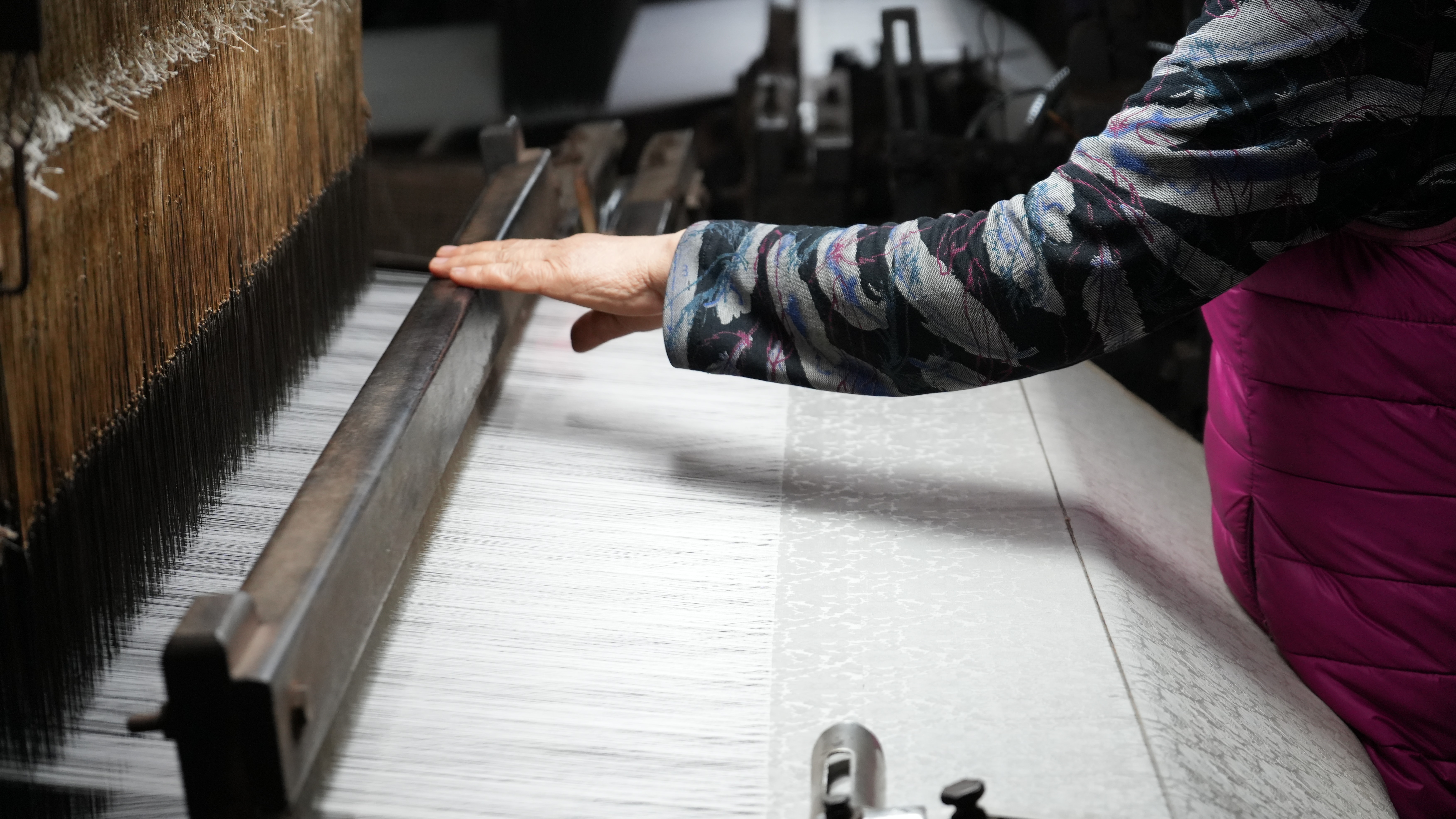 Cận cảnh đôi bàn tay chai sần của nghệ nhân đang tỉ mỉ dệt từng sợi tơ trên khung cửi cổ (Ảnh_ Quỳnh Trang)