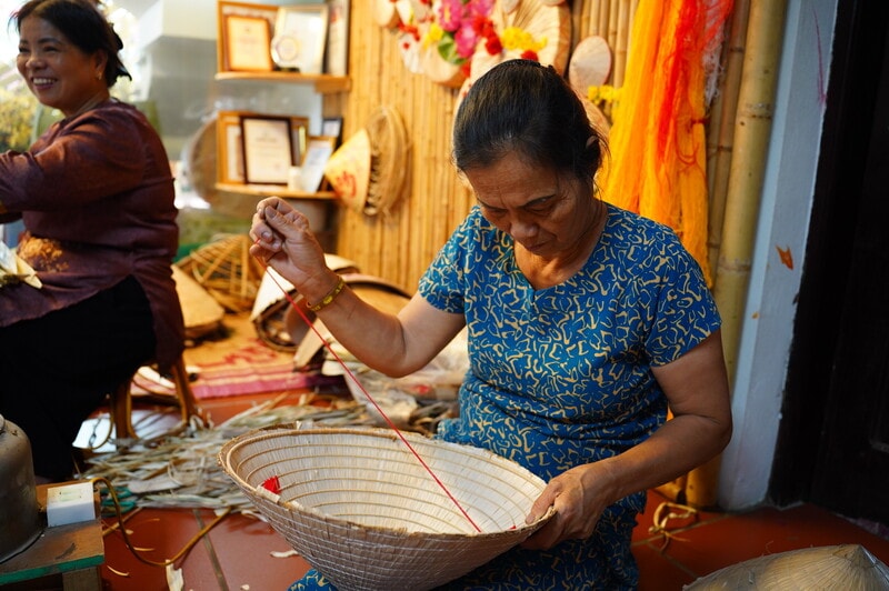 Ở công đoạn cuối cùng, lồng nhôi, người thợ sẽ luồn sợi chỉ màu ở mặt trong của nón, kéo căng và ghim vào đúng các điểm cần giữ để cố định phần quai, hoàn thiện kết cấu sử dụng. Chi tiết nhỏ này đòi hỏi sự cân đối và chính xác ở từng vị trí, để khi đội, chiếc nón vừa chắc, vừa gọn.